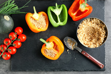 Composition with quinoa stuffed peppers and vegetables on kitchen table