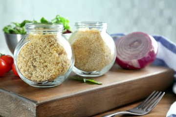 Composition with jars of quinoa and vegetables on table