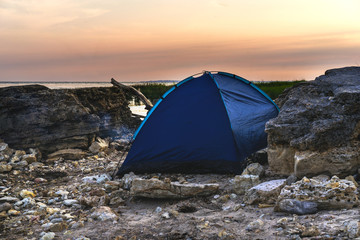 Tent on the stone beach of the sea. Sunset time.