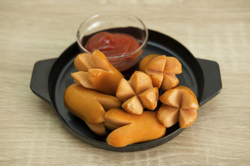 SAUSAGE ON BLACK PAN
Fried sausage in a black pan with ketchup dip.