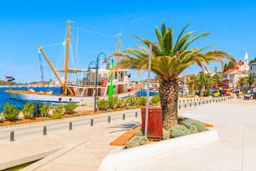 Beautiful traditional sailing boat anchoring in Rogoznica port along coastal promenade with palm trees, Dalmatia, Croatia