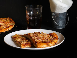 Pizza with sausage and cheese in a white plate on a dark background