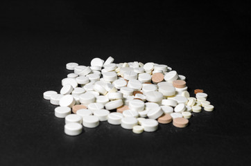 Fototapeta na wymiar Handful of pills on a black background closeup top view