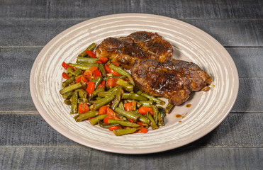 Steamed steaks with beans and bell peppers on a plate top view