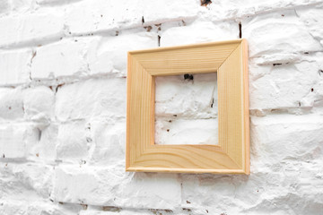 Square wooden frame on a white brick wall