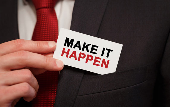 Businessman putting a card with text Make it happen in the pocket