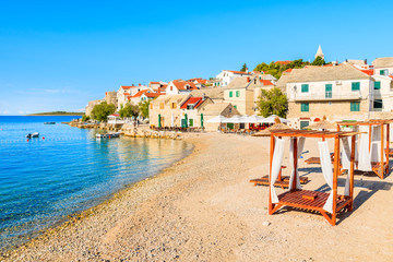 Sunbeds on beautiful empty beach in Primosten old town, Dalmatia, Croatia