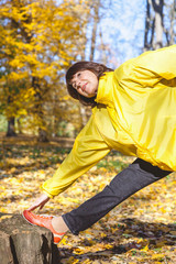 Active elderly woman doing gymnastic exercises in forest glade