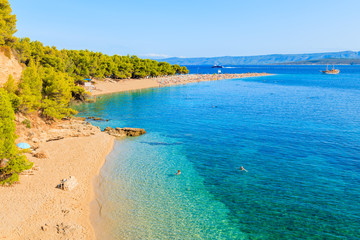 Couple of people swimming on famous Zlatni Rat beach with beautiful sea water in Bol town, Brac island, Croatia