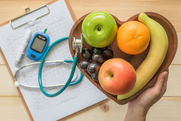 Cholesterol diet and healthy food nutritional concept with clean fruits in heart dish with...