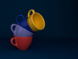 Bend of four cups of coffee of different vibrant colors.