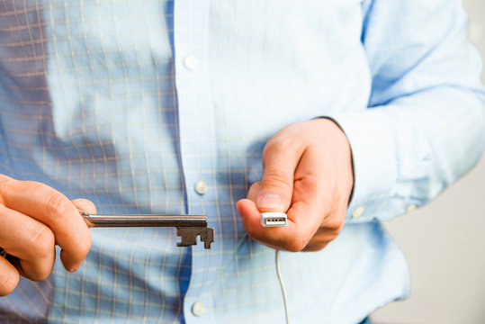 Man holds a key in his hand and tries to open USB. Cyber security and data security on the memory card against hacking. Isolated, white background.