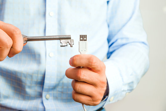 Man holds a key in his hand and tries to open USB. Cyber security and data security on the memory card against hacking. Isolated, white background.