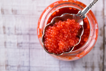 Red and black caviar in small silver spoon on a wood background with black bread ,food concept