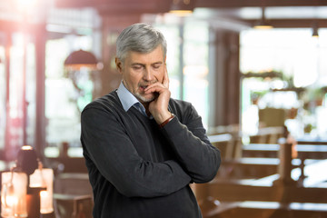 Portrait of deeply thoughtful mature man. Seriously thinking elderly man on blurred background.