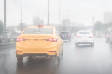 Drive yellow taxi in rain on asphalt wet road. Clouds and sun.