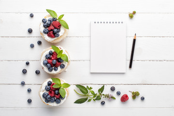 Fototapeta na wymiar Notebook mock up and homemade millefeuille with berries and mint leaves on white background. Top view, flat lay.