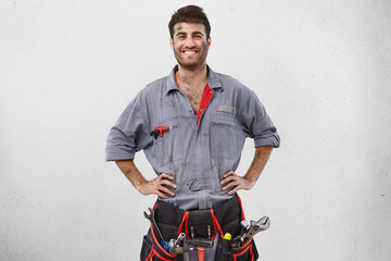 Successful professional attractive young construction worker or mechanic with dirty face wearing...