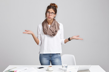 Portrait of young mananger feeling tired and unhappy, puffing cheeks, gesturing with open palms, looking up, fed up with stressful bad working day, counting down minutes to leave office and go home