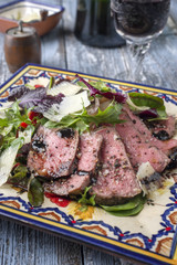 Traditional Italian Tagliata di Manzo Steak with Parmesan and Salad as close-up on a plate