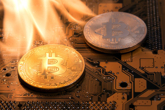 Gold and silver Bitcoins are on fire on the tracks of an electronic computer board.