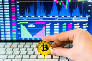 Hand hold gold bitcoin and trading chart background. Virtual currency concept.