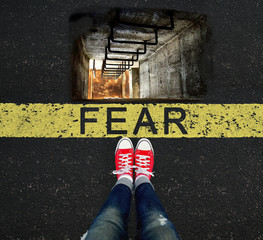 Girl standing in front of the FEAR sign and a well that scares