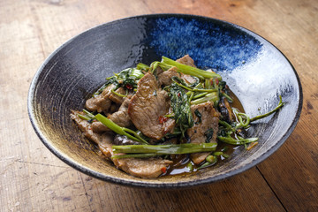 Traditional stir fried Thai pad nua with morning glory as close-up in a bowl © HLPhoto