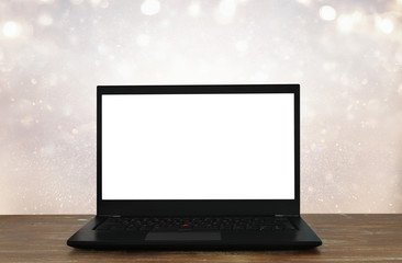 Fototapeta premium open laptop with white screen on wooden table in front of abstract glitter background