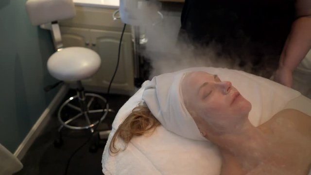 Massage receives a steam treatment on her face during her facial. Steadicam shot.