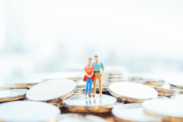 Financial concept. Miniature people: Small couple figures in love standing on stack of coin.