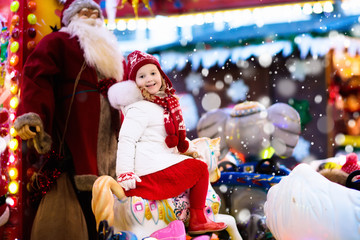 Child on Christmas fair. Kid riding Xmas carousel
