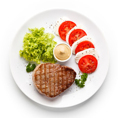Grilled beef steak with mozzarella and vegetables on white background 