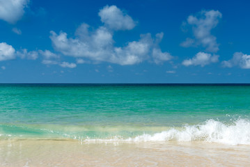 blue sea and white wave on beach with blue sky and clouds on sunny day