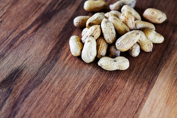 Roasted peanuts on wooden background in selective focus. Vintage color.