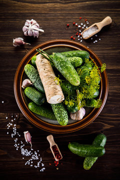 Raw cucumbers, garlic, horseradish and fennel on wooden background