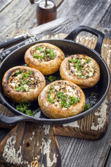 Traditional Italian mushroom caps stuffed with feta as close-up in a rustic frying pan