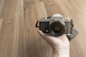 man holding Film Camera in Front Panel with wooden background