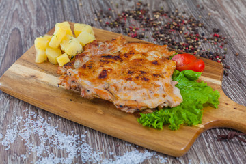 chicken grilled chicken on a wooden board, to boiled potatoes and greens