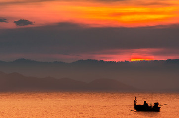 A fisherman has alone on the sea in the evening with big sunset time at Thailand.