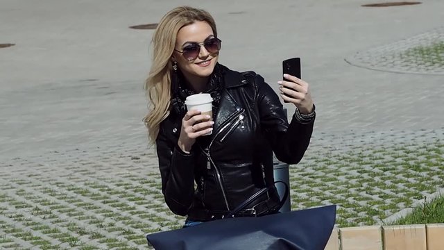 Fashionable girl in leather jacket taking a selfie on smartphone