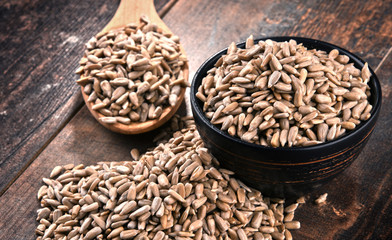 Composition with bowl of shelled sunflower seeds on wooden table