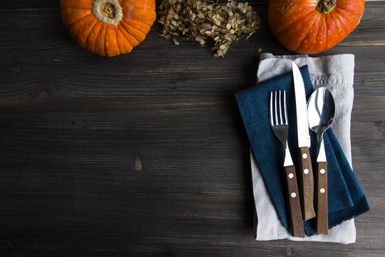 Thanksgiving, Halloween, food background - wooden table with cutlery and pumpkins. Top view. Copy space.