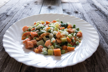 A cocktail of frozen chopped vegetables ,on rustic wood
