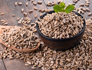 Composition with bowl of shelled sunflower seeds on wooden table