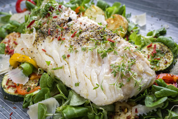 Fried cod fish fillet with lettuce and vegetable as close-up on a plate