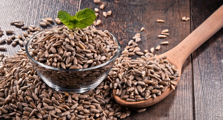 Composition with bowl of shelled sunflower seeds on wooden table