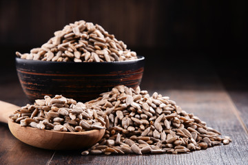 Composition with bowl of shelled sunflower seeds on wooden table