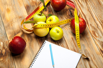 Apples, a diet plan and a centimeter on a wooden background