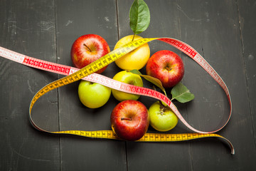 Diet and centimeter, apples on a black wooden background